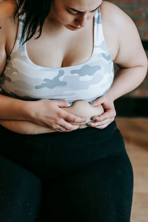 Mujer con sobrepeso tocando su abdomen